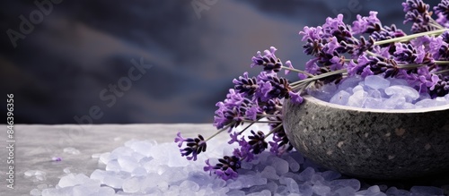 A copy space image featuring a composition of bath salt and freshly picked lavender flowers on a backdrop of basalt stone