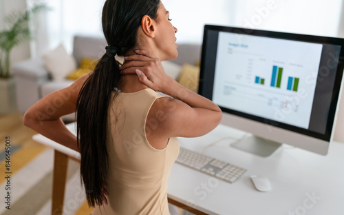Tired woman massaging rubbing stiff sore neck tensed muscles fatigued from computer work