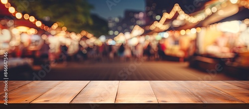 Wooden tabletop with no objects on it, blurred night market in the background, and selective focus, ideal for showcasing products with copy space image.