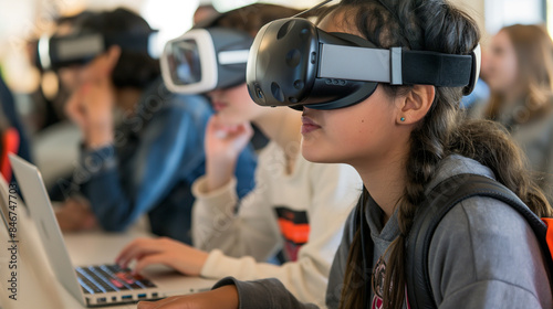 Um grupo de alunos usando fones de ouvido VR, com um aluno usando a tecnologia para interagir e se envolver em uma experiência educacional enquanto outros assistem em seus laptops ou smartphones
