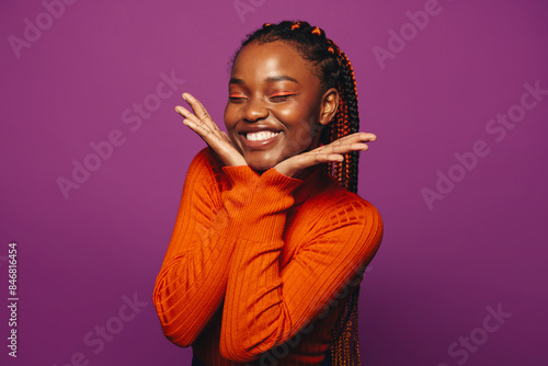 Vibrant young woman with two tone braids celebrating on a colourful purple background