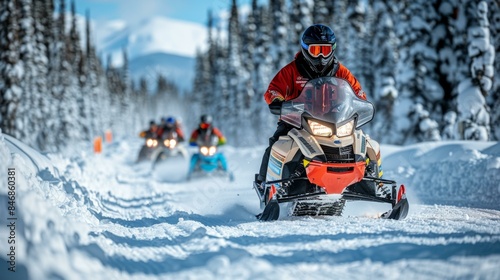 A group of people riding snowmobiles down a snowy mountain trail.