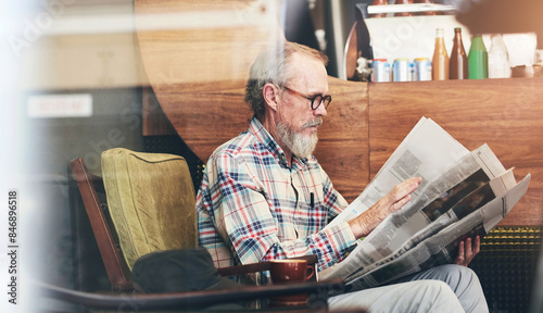Newspaper, cafe and senior man reading business information for financial stock market. Window, glasses and elderly male person enjoying economy headlines in journalism article in coffee shop.
