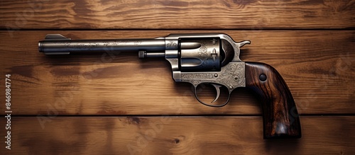 A handgun with a short barrel and stock, suggestive of a revolver, placed on a textured wooden tabletop. with copy space image. Place for adding text or design