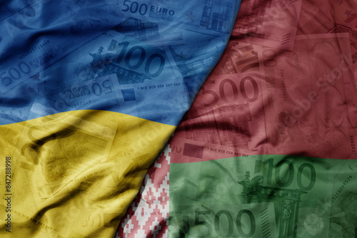 big waving realistic national colorful flag of belarus and national flag of ukraine on a euro money banknotes background.