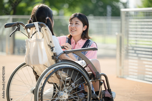 車椅子に乗る子供と介護や補助をする介護士や看護師 上半身 ホームヘルパーやデイサービスのイメージ
