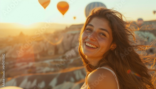 woman with long brown hair taking a selfie while flying in a hot air balloon over Cappadocia and smiling at the camera