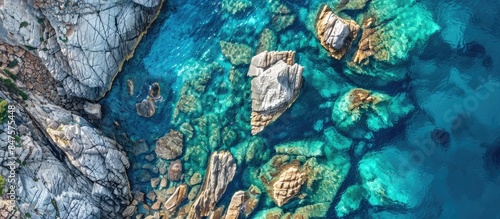 Aerial perspective of rocky formations and crystal clear blue ocean waters. Stunning backdrop of the sea with room for text.