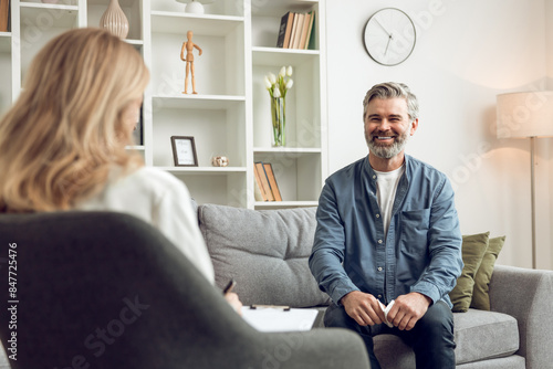 Man patient during therapy session with blonde woman psychologist in medical clinic