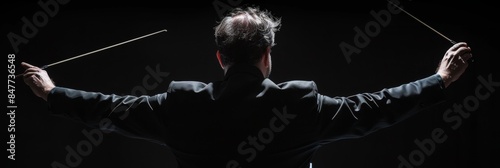 Professional conductor with baton on black background