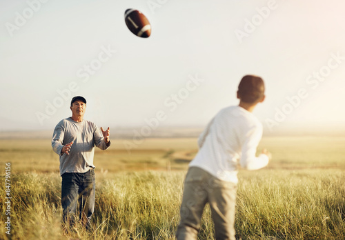 Father, son or American football in outdoor for bonding, skills practice with dad in nature. Male person, boy child and development or training in countryside, together for exercise or learning sport