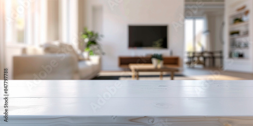 frontal view shot of empty white table in living room, white blurred living room with tv and furniture in the background