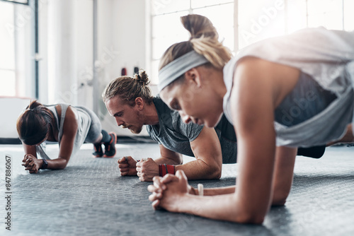 Fitness, personal trainer and plank exercise with group, healthy workout or training in gym for weight loss. Athlete, man and women together for power challenge, strong muscle at club or commitment