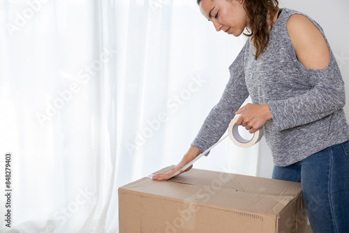 Happy young woman packing her things to move to her new house. She is a homeowner, mortgage concept. New home, new life