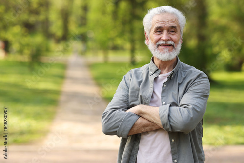 Portrait of happy grandpa with grey hair in park, space for text
