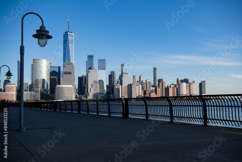 Lower Manhattan and One World Trade Center in New York City, USA as seen from Weehawken New Jersey. Skyscrapers of Manhattan located near rippling water of New York bay against blue sky.