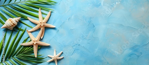 Top view of summer vacation background featuring starfish, rudder, and green palm leaf with space for text