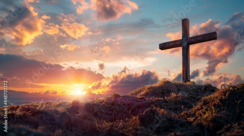 Wooden cross firmly planted in the soil on a peaceful hill, under a vibrant sunset sky, evoking the prayer and sacrifice of Jesus Christ