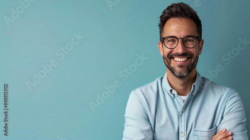 Smiling businessman wearing eyeglasses working on laptop while standing on blue background