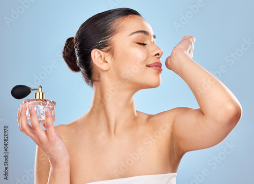 Perfume, fragrance and woman with wrist smell for clean scent and beauty salon aesthetic in studio. Wellness, model girl and parfum bottle with spray skin for self care and fresh by blue background