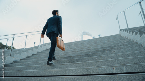 Top view of smart business man walking up stairs with bag in the hand. Professional project manager climb up the stair and going to workplace. Increasing skill, getting promotion, traveling. Exultant.