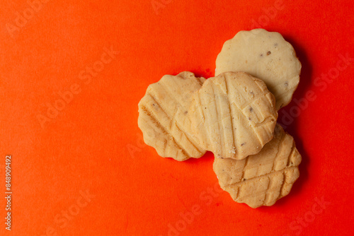 Stacked carrom seed cookies or salted ajwain cookies on an orange background. Top-down view. Food Flat lay.