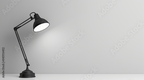 A black metal table lamp with a bright light illuminates a desk on a light background.