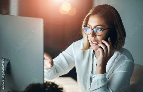 Computer, night and phone call with business woman in office for design or web development. Conversation, internet and research with creative employee at workplace desk for communication or feedback