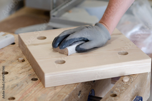 Carpenter hand. Grinding wooden board with sandpaper in carpentry workshop