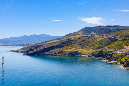 Vista panorámica de la costa de Castelsardo, Cerdeña, Italia El mar Tirreno, de un azul profundo, se extiende junto a colinas verdes y acantilados escarpados, ofreciendo un paisaje natural.
