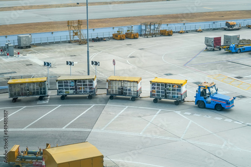 Baggage carts in the train carry passengers suitcases for loading onto the plane.