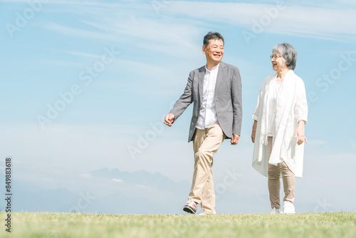 公園・旅行先を話しながら歩く高齢者夫婦（シニア・男女） 