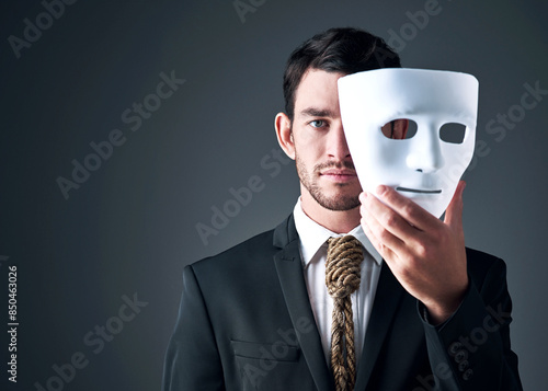 Portrait, business man and spy with mask in studio isolated on gray background. Fake face, suit and industrial espionage disguise of agent with rope noose for secret identity, confidential or fraud