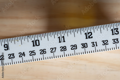 detail of a white measure in inches and centimeters on a wooden surface