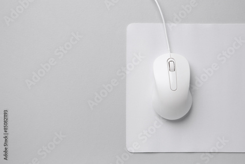 Wired mouse with mousepad on grey background, top view. Space for text
