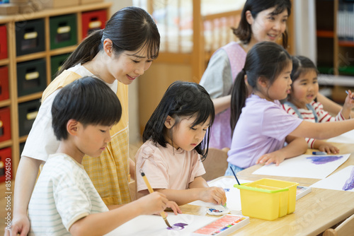 学童や放課後デイサービス等で勉強をする先生と生徒 小学生複数