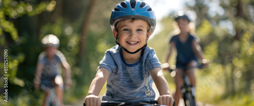 A young boy wearing a safety helmet and riding his bike on the path with family in the background, all smiling at the camera