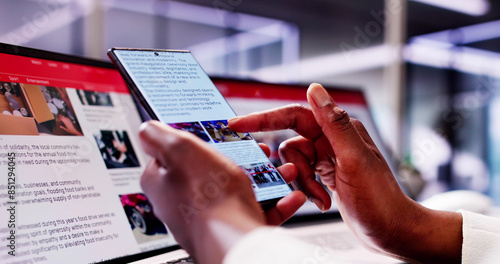 African American Woman Reading Online News on Smartphone and Laptop: Keeping Up