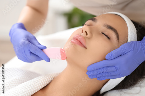 Beautician with wax removing woman's hair on chin in salon, closeup