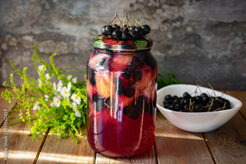 Preparation for winter: compote of rowan and pears in a glass jar on a wooden table. Close-up