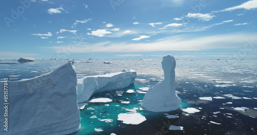 Iceberg melt at turquoise ocean bay in sunny day. Crashed glacier drifts in ocean, floating ice floes. Ecology, melting ice, climate change global warming. Antarctica majestic landscape drone view