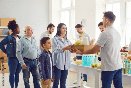 Group of diverse poor people getting food aid at a non profit organization center. Team of volunteers giving multiethnic needy citizens food and hygiene supplies. Help, charity and donation concept