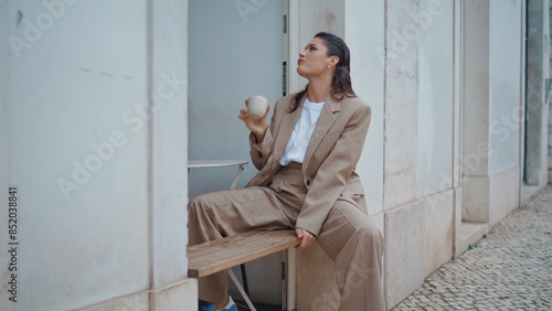 Business woman sipping tea in open air coffeehouse. Relaxed girl resting