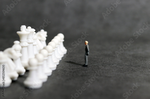 A miniature businessman and pawn standing on a dark background. Business decision-making concept. 