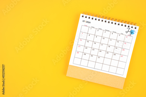 July 2024 desk calendar on yellow background, position with copy space.