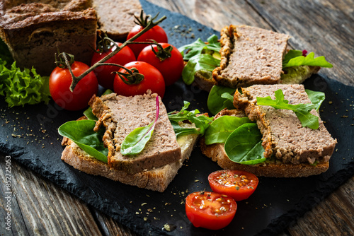 Tasty sandwiches with liverwurst and chive on wooden table 