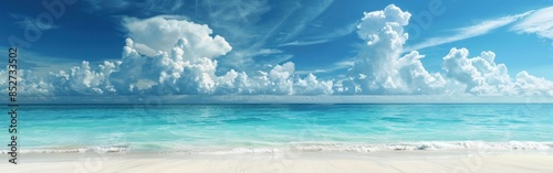 A serene landscape of a white sandy beach with gentle waves lapping at the shore. The crystal clear turquoise water extends into the distance, meeting the horizon beneath a vast blue sky dotted with f