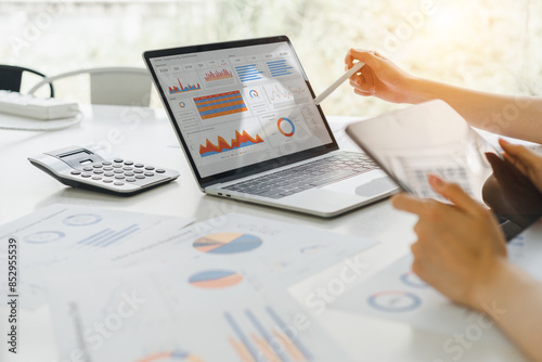 Professional analyzing financial data graphs, charts on laptop display at a modern workspace. Financial analysis or business evaluation concept