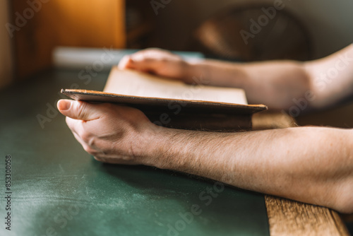 Reading books. Man reading a book at a wooden table.Male hands leafing through a book in the library in a dark room.Knowledge concept.Open book in hands. Literature and reading concept. 