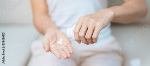 woman hand holding medicine painkiller pill on the sofa at home, taking for headaches, stomach ache, Diarrhea Pain from food poisoning, Endometriosis, Hysterectomy and Menstrual